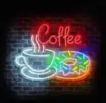 Neon LED kawa i donut na ceglanej ścianie.