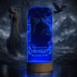Personalizowana lampka LED z grafiką wikinga, nickiem HROD_87 i niebieskim podświetleniem na drewnianej podstawce.
