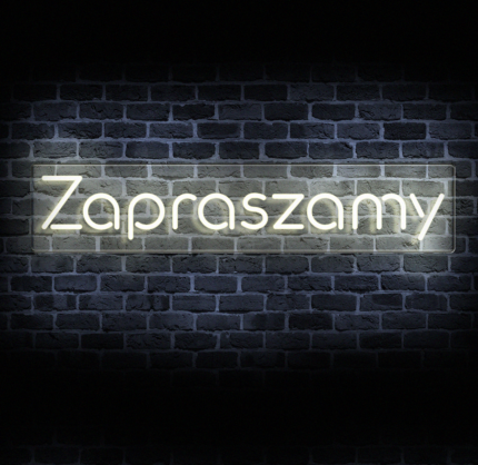 eon napis zapraszamy LED w ciepłej bieli na przezroczystej plexi, na tle ceglanej ściany