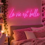Neon La vie est belle – różowy napis LED nad łóżkiem w sypialni